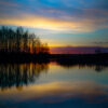 A body of water with trees and a sunset
