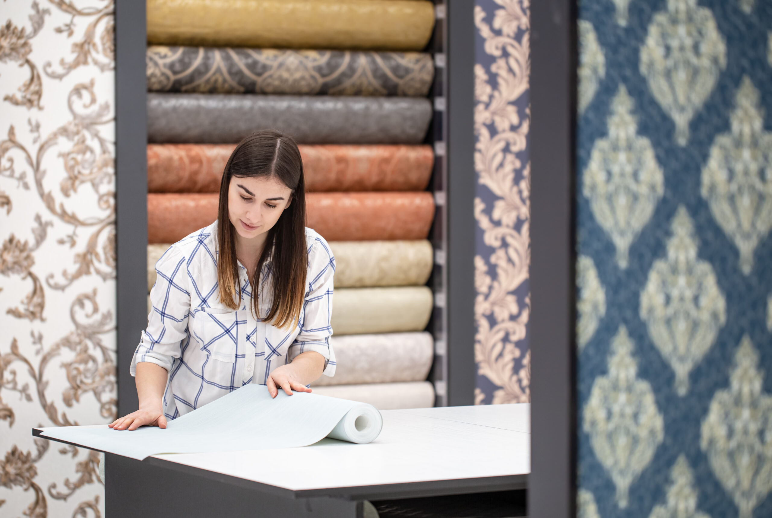 A young woman in a store chooses Wallpaper for her home.
