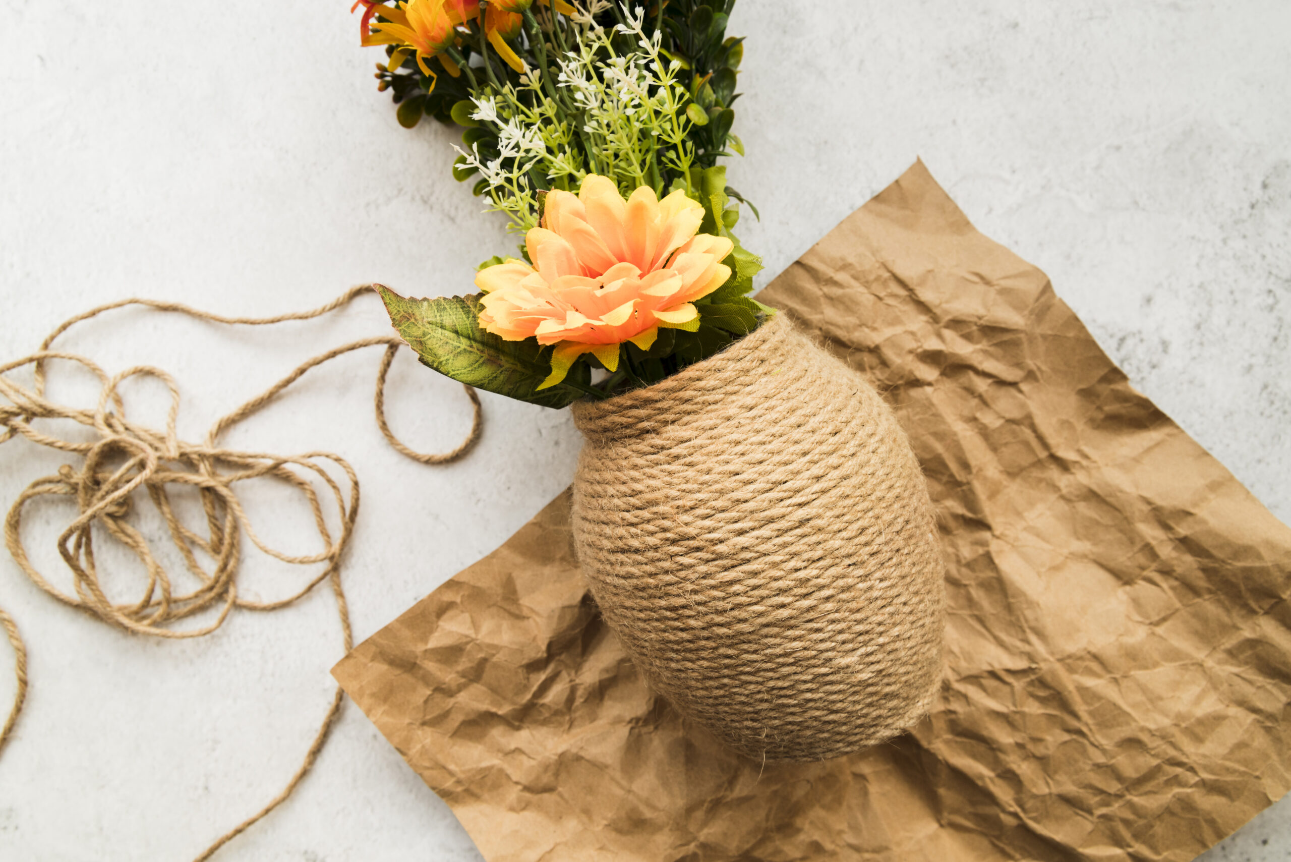 vase-made-with-string-crumpled-brown-paper-against-white-backdrop