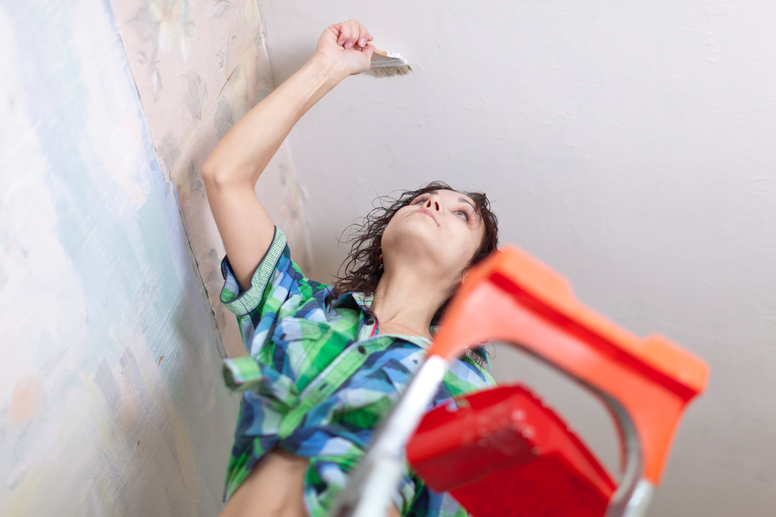 girl paints ceiling at home